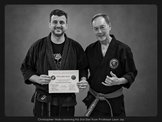 Christopher Hicks standing beside Grandmaster Leon Jay, holding his 2nd Dan certificate